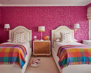 colorful children's bedroom with pink Designers Guild wallpaper and checked throws