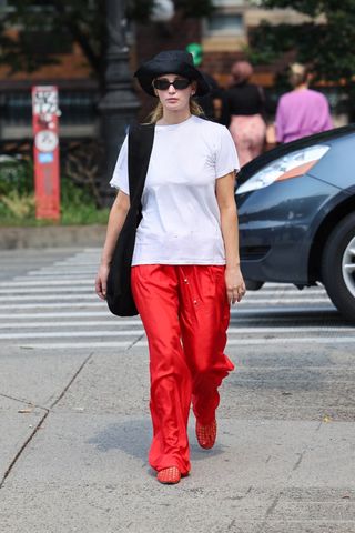 Jennifer Lawrence vestindo uma camiseta branca, calça vermelha e sandálias gelatinosas vermelhas do The Row em Nova York.