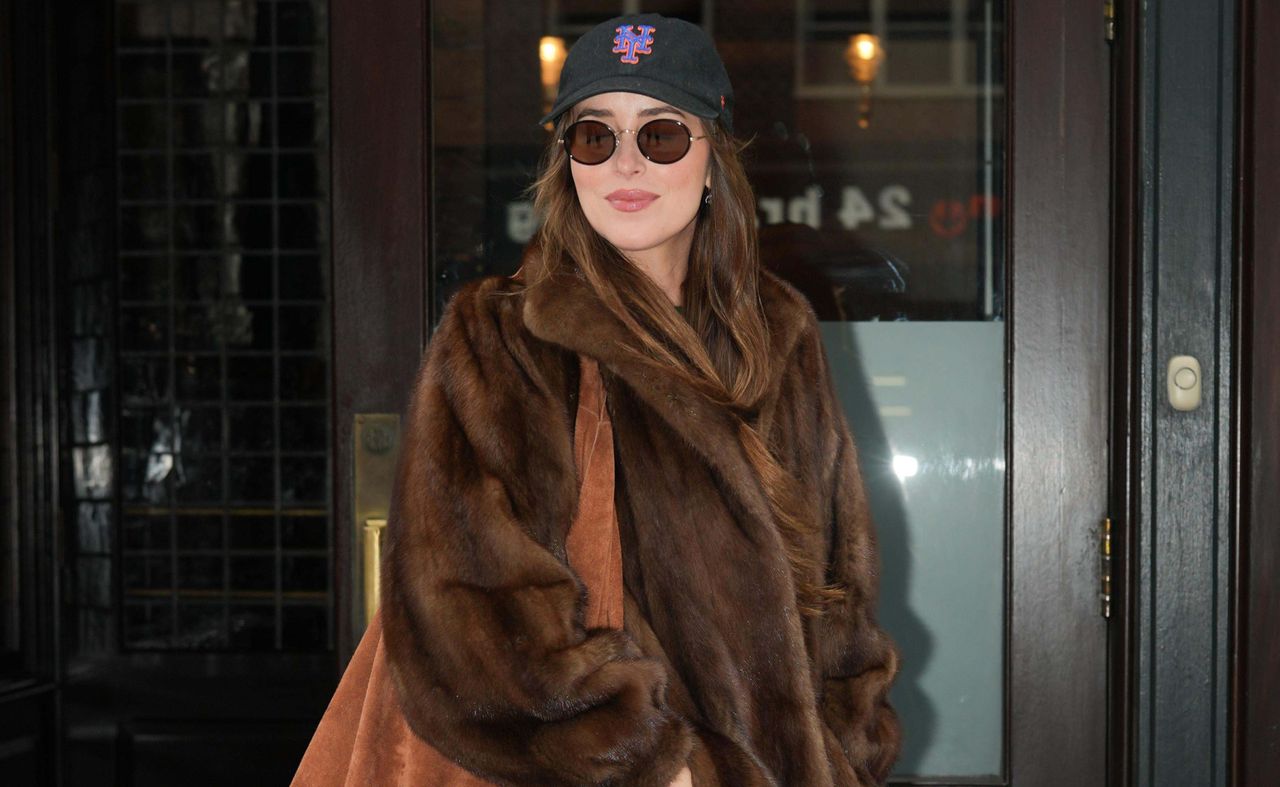 Dakota Johnson wearing a fur coat and mets hat in New York City