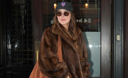 Dakota Johnson wearing a fur coat and mets hat in New York City