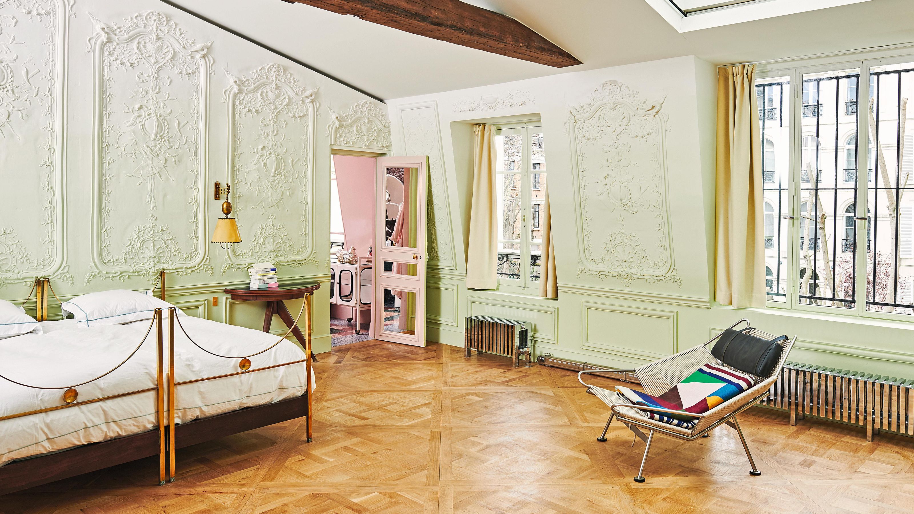 a pale green ornate bedroom in a parisian apartment with vintage italian furniture