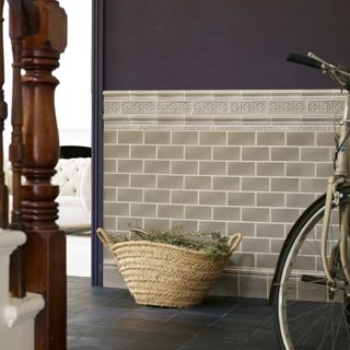 hallway wall decor ideas, hallway with stone coloured metro tiles, aubergine wall colour, grey tiled floor, basket, bike