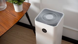 An air purifier in a living room, with a modern white shell and PM 2.5 dust protection