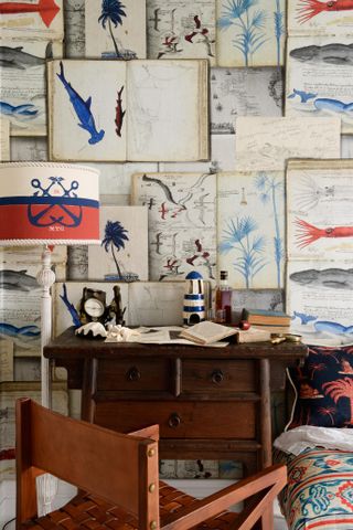 blue and white home office with marine themed wallpaper and dark wood furniture