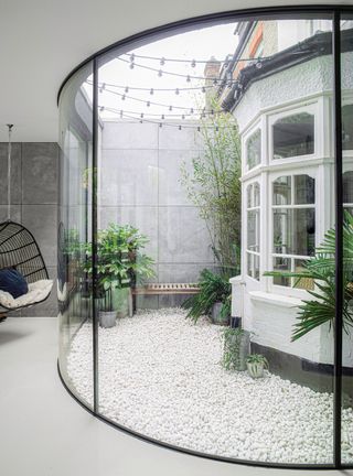 a curved glass sunroom with a hanging chair
