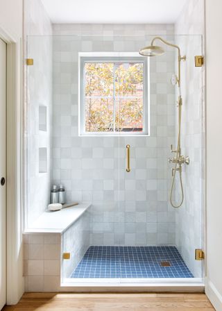 Shower with square white tile and blue tile base and built in seat