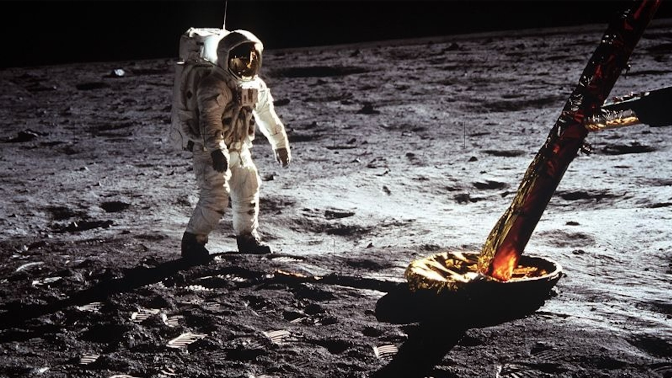photo of an astronaut in a white spacesuit on the surface of the moon
