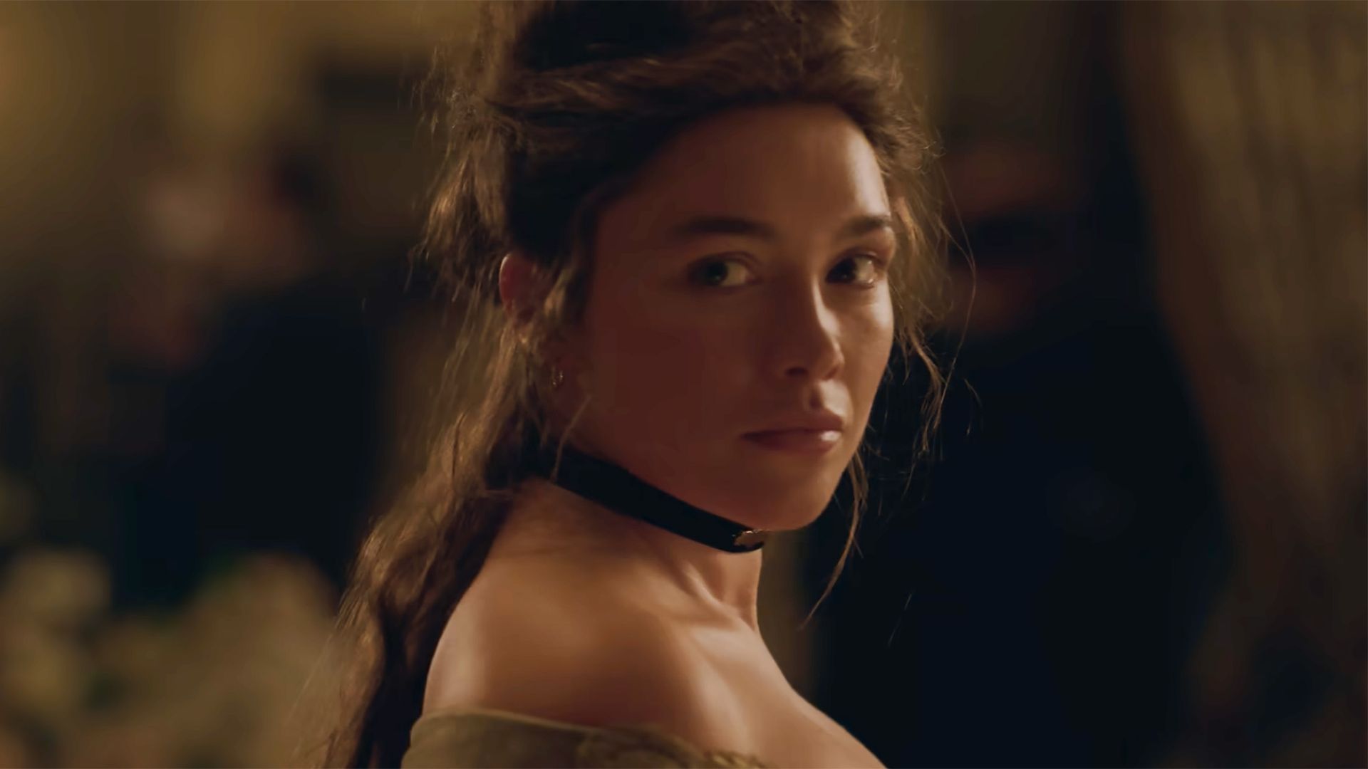Florence Pugh looks back behind her with a black ribbon choker around her neck. Her hair is in an updo.