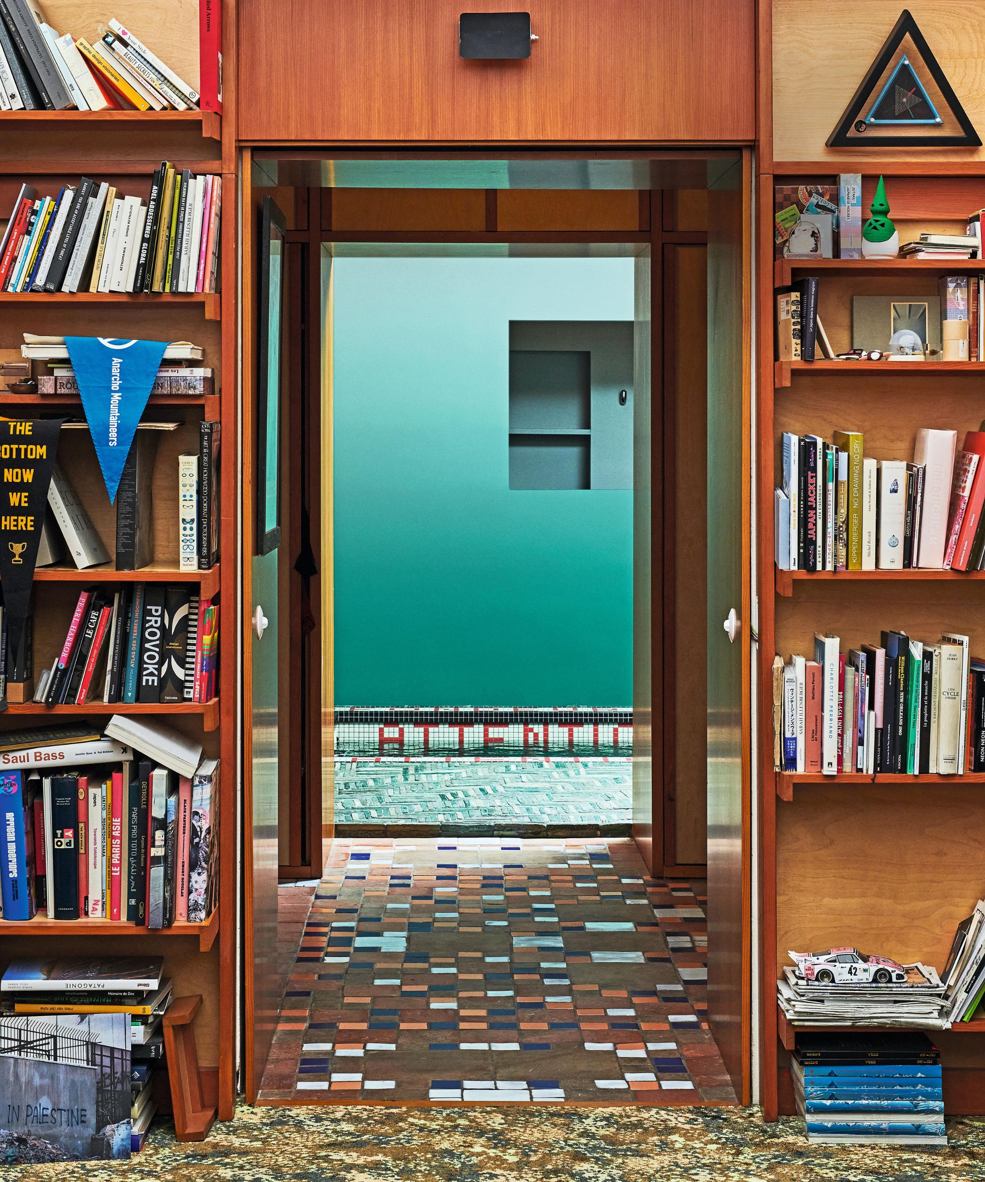 a mid century wooden bookcase built round a doorway with multi colored tile