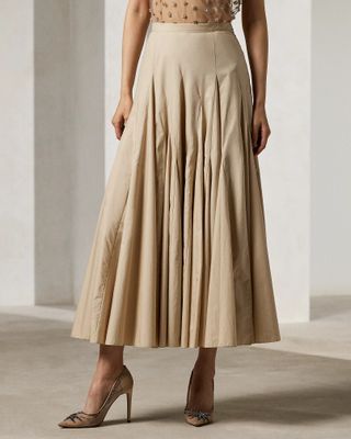 a model wears a beige pleated A-line midi skirt