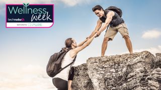 Man hauling woman over rock during hike
