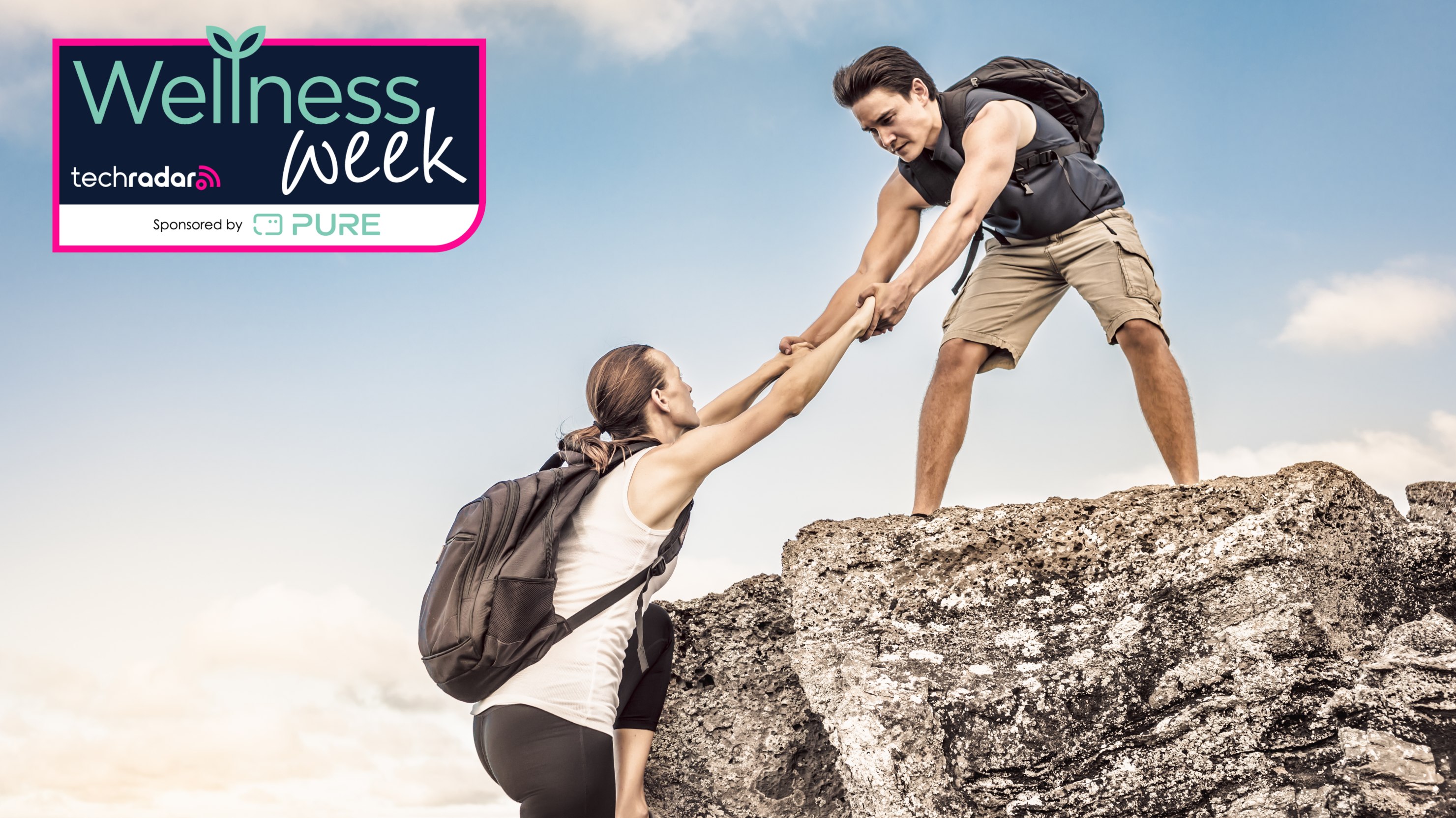 Man hauling woman over rock during hike