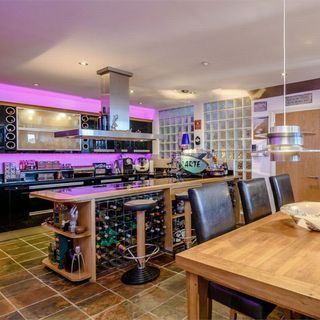 futuristic vibe to this expansive kitchen with it’s vibrant violet backsplash and the space-ship like chrome ceiling drop lamp