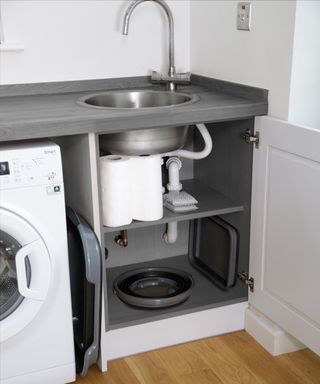 A black and grey collapsible bucket under the sink