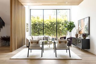 living room with pale wood screen from stairs and white armchairs