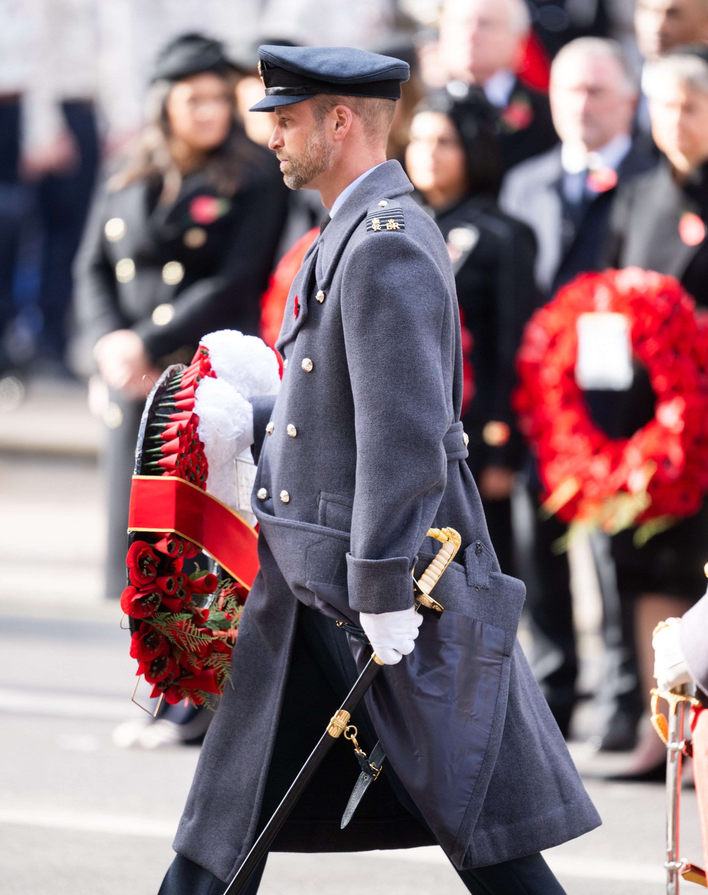 Prince William wearing a gray coat and holding a wreath