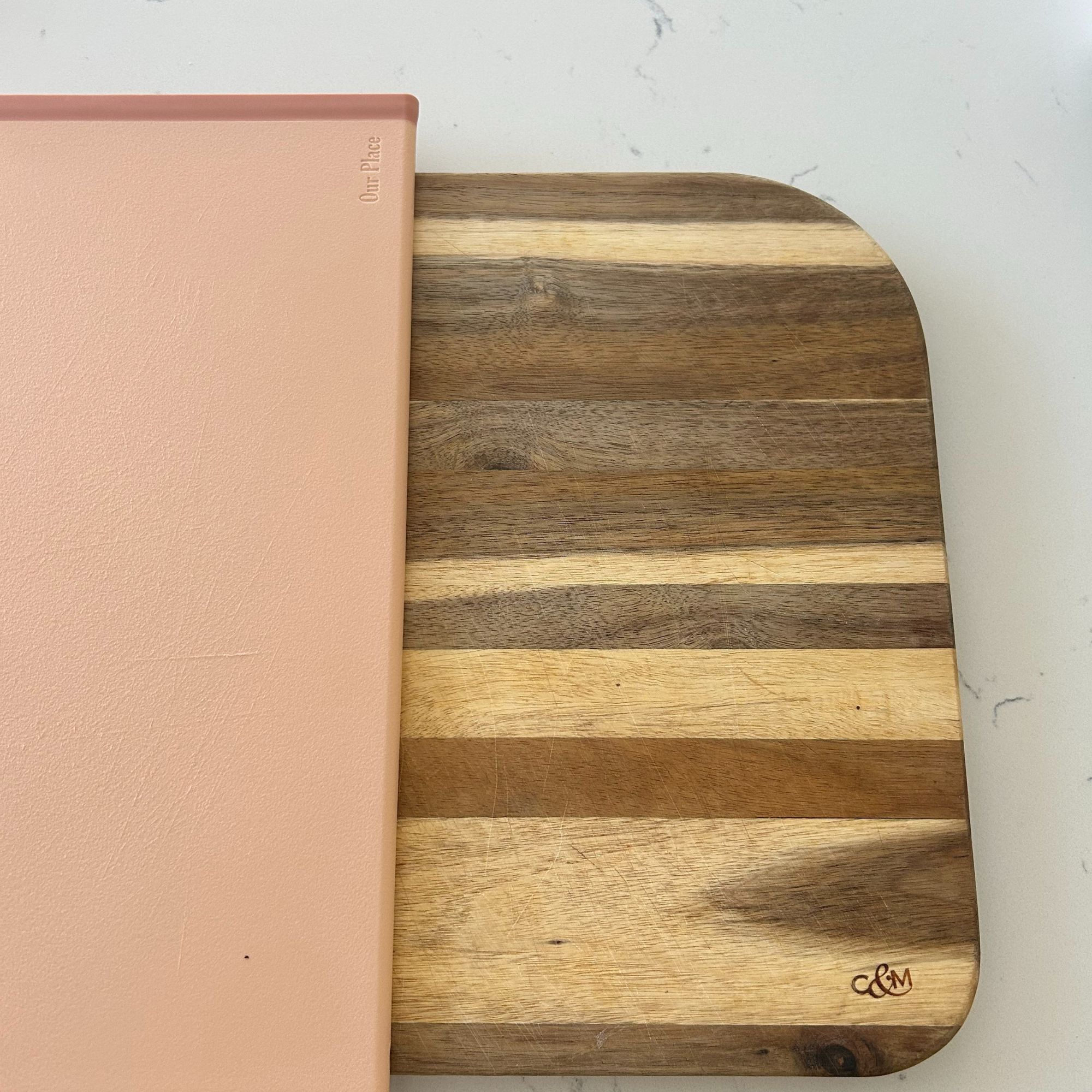 Wooden Cole &amp;amp; Mason chopping board and pink plastic Our Place chopping board on worktop