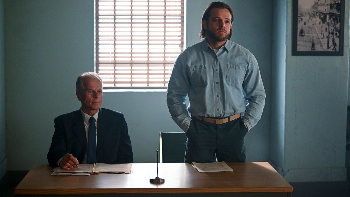 From left to right, a lawyer sitting down and Bode standing up from a table during his hearing in the Fire Country Season 1 finale.