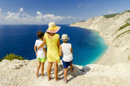 Mother and sons embracing admiring the idyllic Ammos beach standing on top of cliffs, Kefalonia, Ionian Islands, Greece.