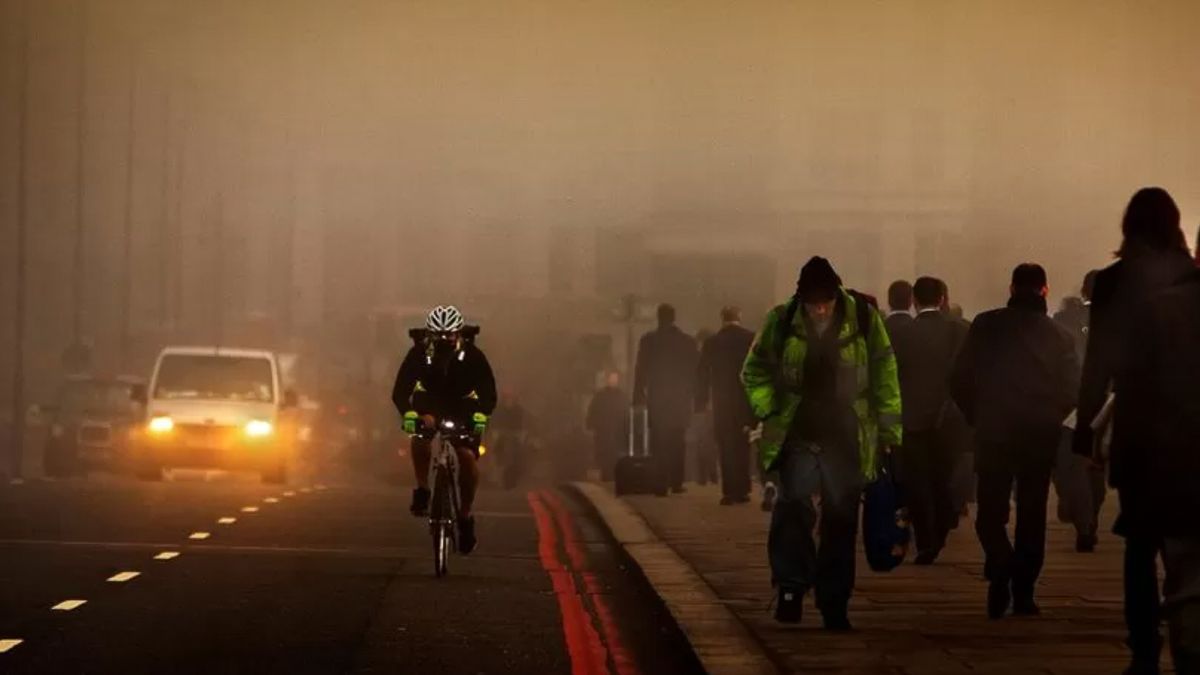 A cyclist on a busy urban street shrouded in smog