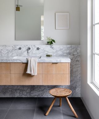 A bathroom with marble splashback and white oak vanity