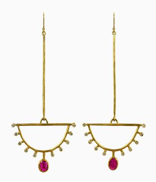 Gold dangly earrings with rubies hanging from them