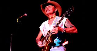 Dickey Betts wears a cowboy hat as he plays a Les Paul onstage with the Allman Brothers Band, 1993