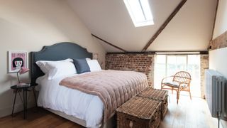small loft conversion with exposed brick wall, skylight and extra window being used as bedroom