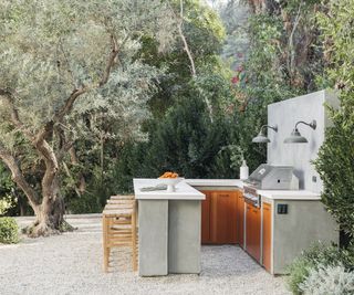 An outdoor kitchen area with bar seating area in a gravel garden