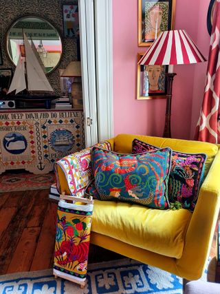 yellow armchair and striped lampshade with view to hall with colorful embroidered artwork