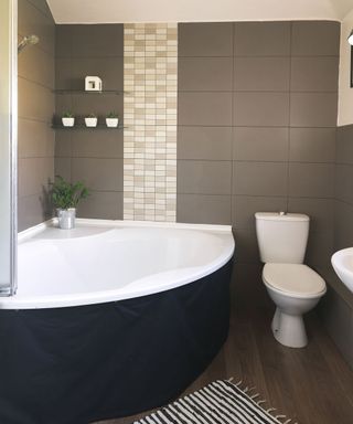 bathroom with grey tiled walls and wooden flooring