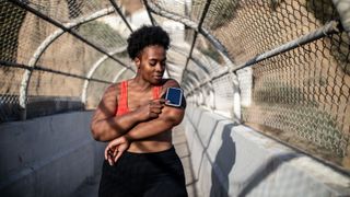 Woman pausing during workout to look at phone holder on her arm