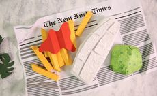 View of Papermeal video props - fish, chips with ketchup and peas made from paper pictured on top of a newspaper