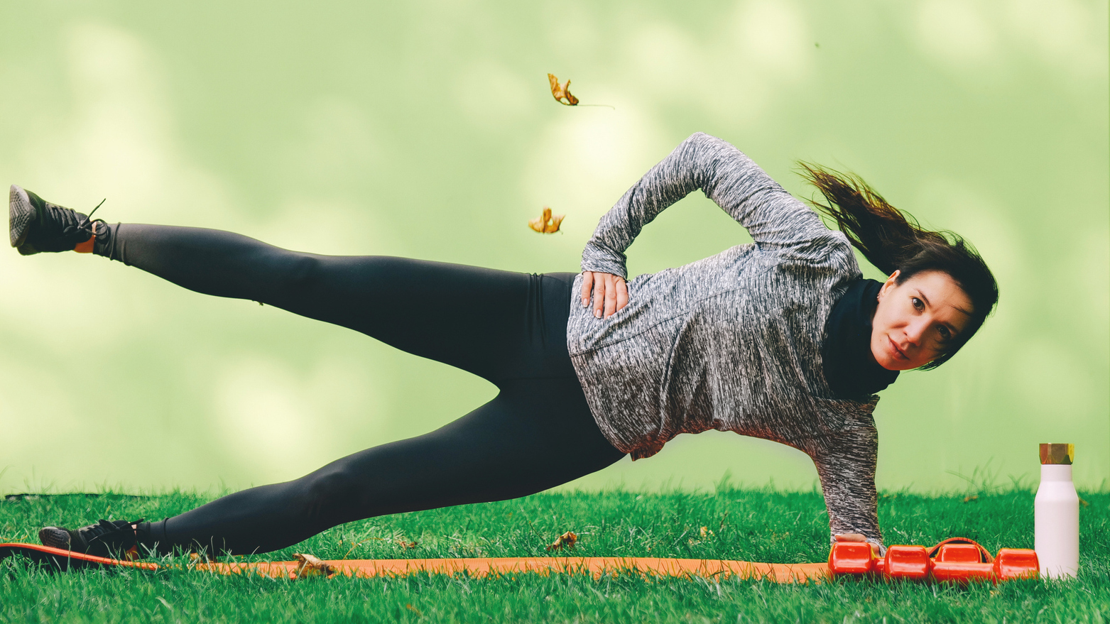 Woman performs side plank with leg lift exercise at home