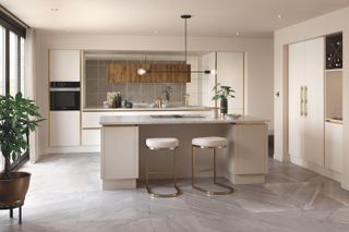 Kitchen with slab doors in neutral finish with gold trim, island, neutral walls and neutral floor tiles