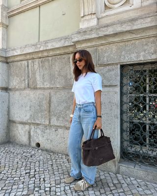 Debora Rosa wearing a white t-shirt, jeans, sneakers, and a big brown bag.