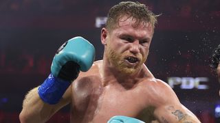 Saúl 'Canelo' Álvarez lanza un puñetazo con guantes de boxeo azul cielo.