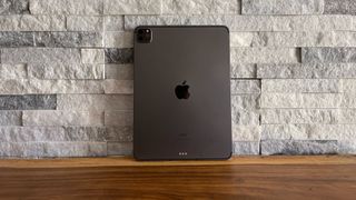 En mørkegrå iPad Pro 11 (2021) står lænet op ad en grå stenmur.
