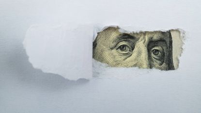 Torn white paper revealing US Currency