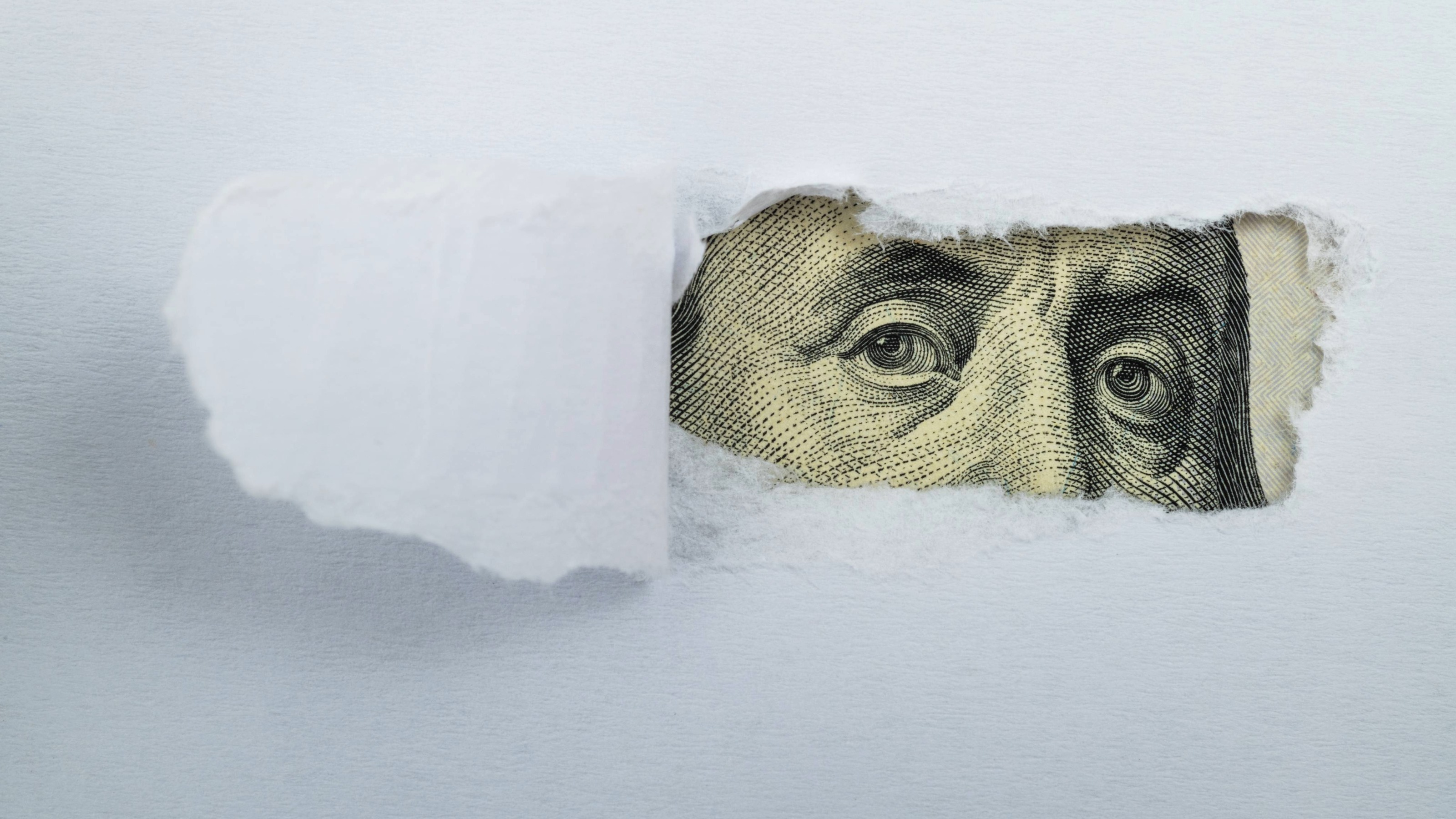 Torn white paper revealing US Currency