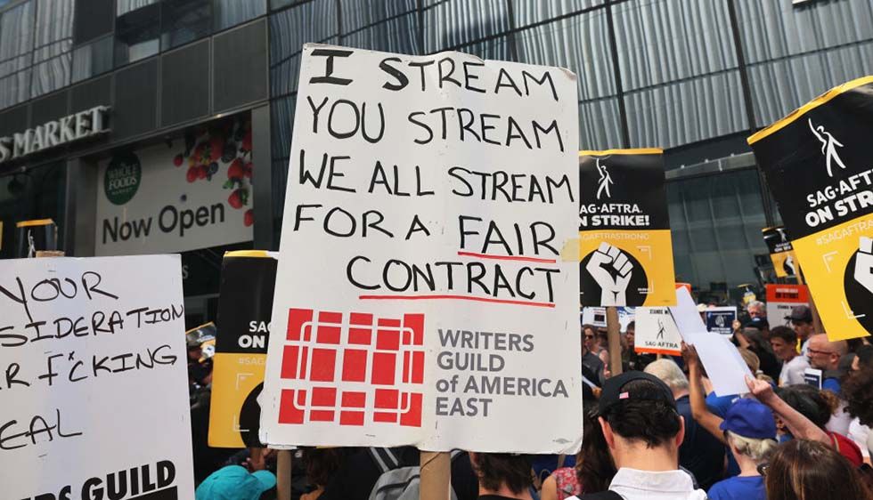 People hold signs as members of SAG-AFTRA and Writers Guild of America East walk a picket line outside of the HBO/Amazon offices during the National Union Solidarity Day on August 22, 2023 in New York City.