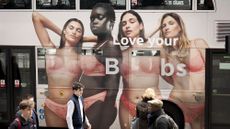 Four women and the sentence 'Love Your Boobs' are seen on the side of a London bus