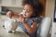 Child putting coins into a piggy bank