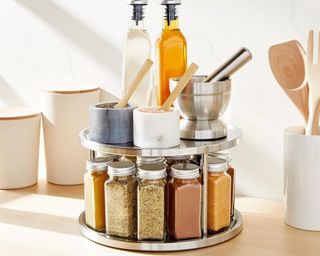 Two-tiered metal lazy Susan with spice jars below, and cooking ingredients including oil canisters on top