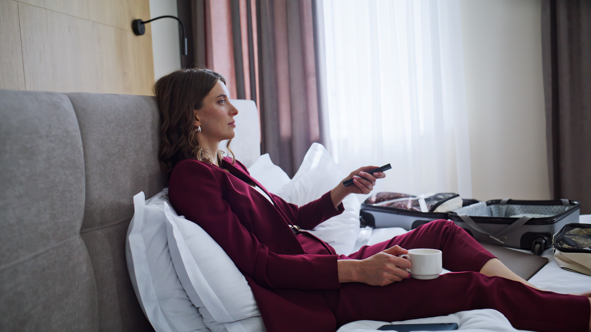 HDMI LA business woman in hotel with remote control sitting on bed