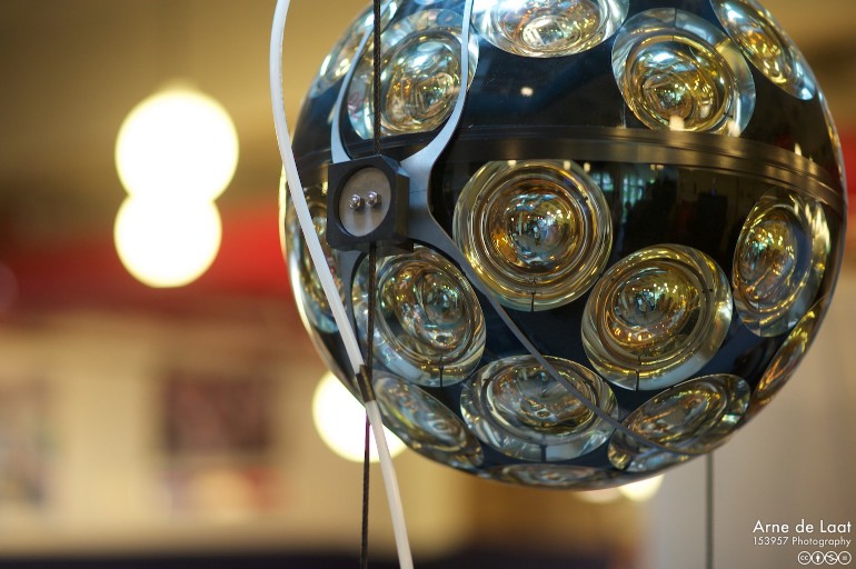 A close up of a black sphere with yellowish glass circular windows all over.