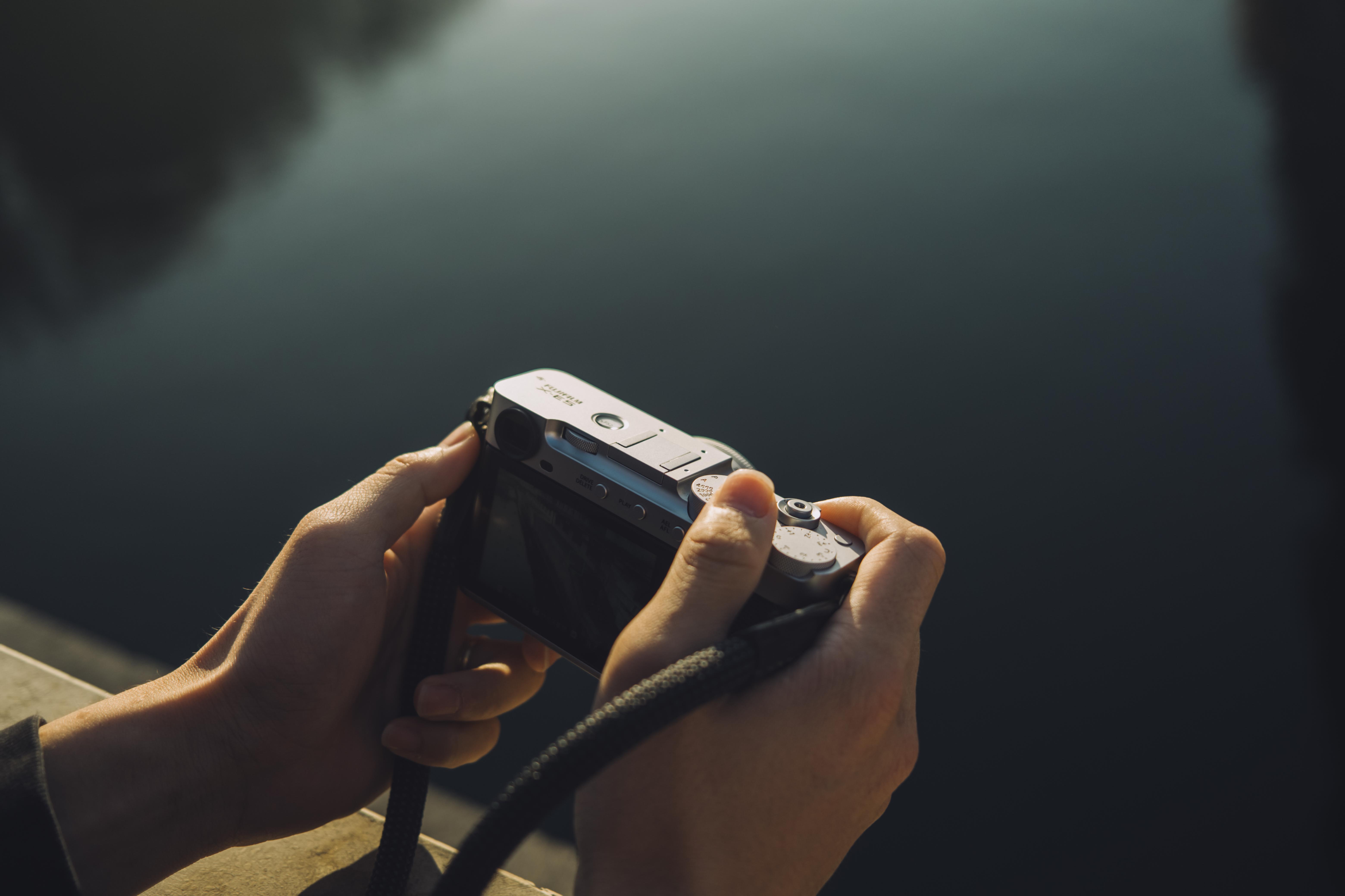 The Fujifilm X-E5 in hand of a person standing on a bridge over a river
