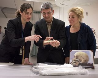 researchers examine a 2,500-year-old bone fragment