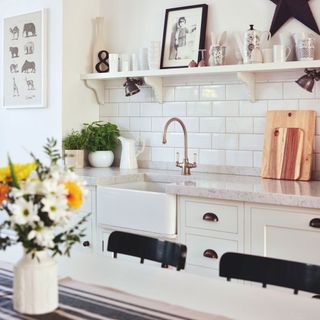 A sink area with metro tiles behind a brass tap and wooden chopping boards