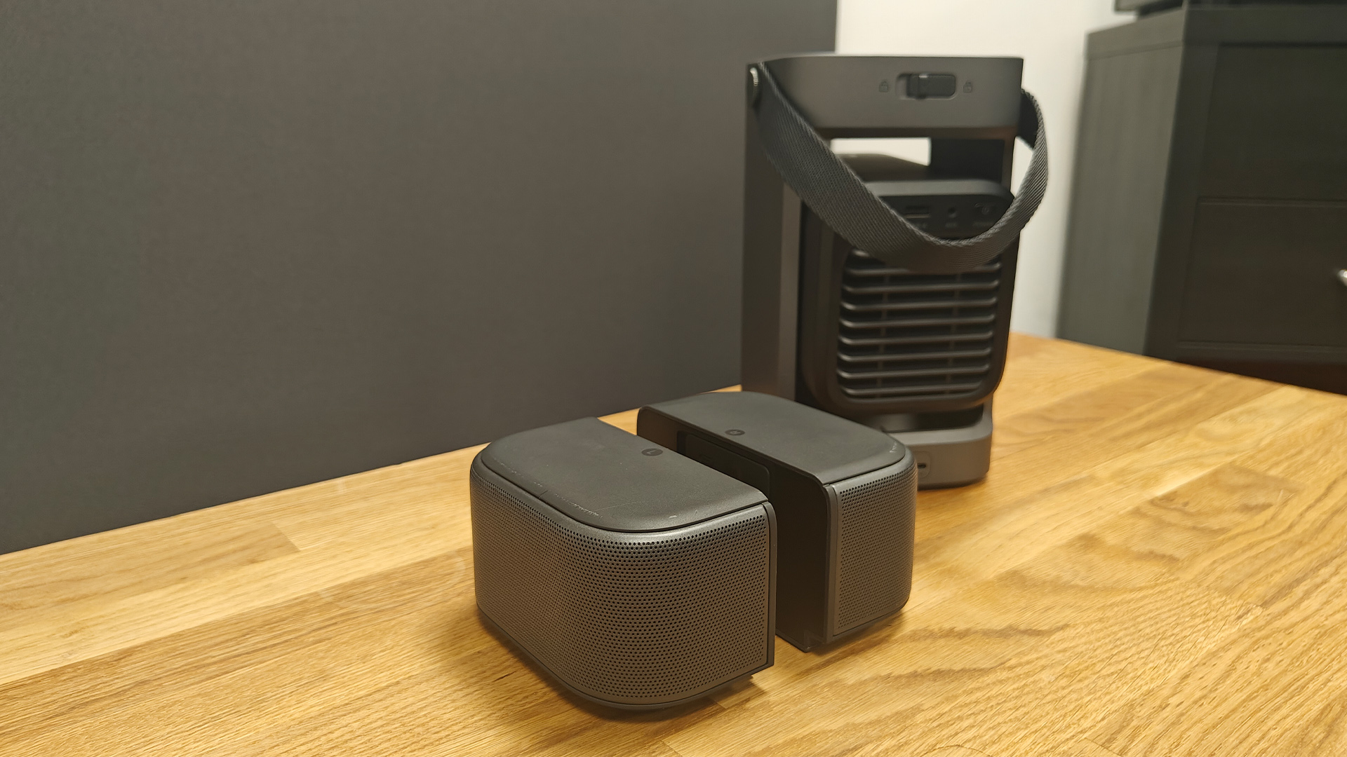 Soundcore Nebula P1 projector on wooden AV rack with speakers separate